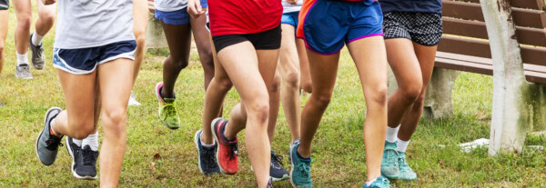 legs of female runners running in a park in a large group