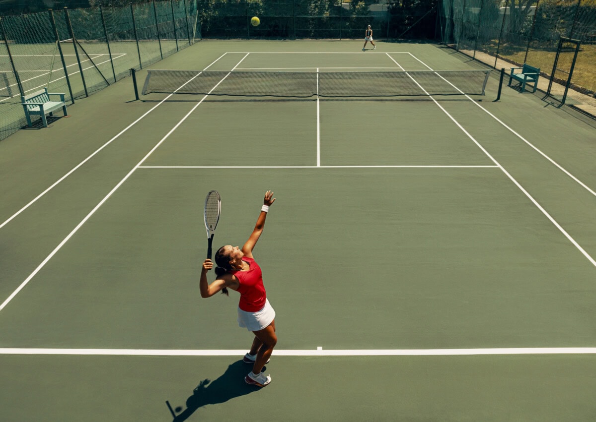 female tennis player serving during match on hardcourt