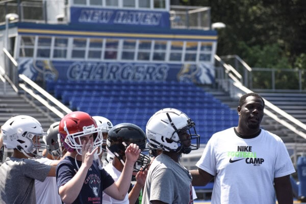 Football team players and coach at New Haven Chargers stadium.